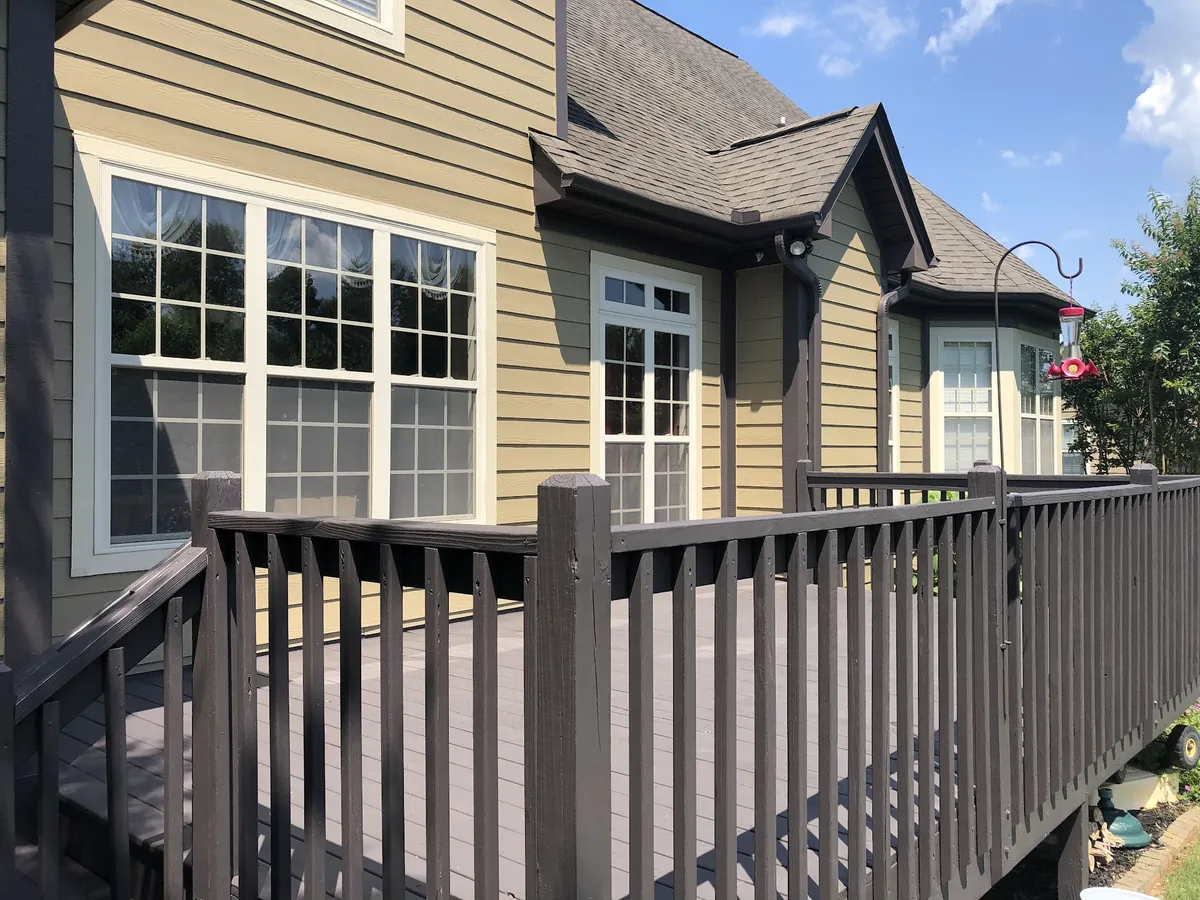Deck railings stained dark brown on a tan two-story home