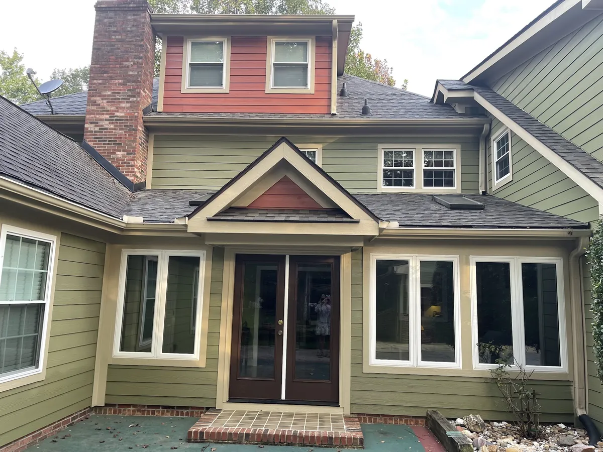 Craftsman home in green siding with red accent gables and cream trim