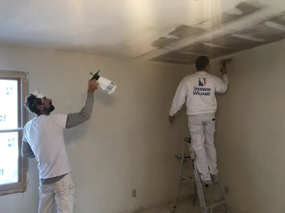 DB Painting crew spraying and rolling a ceiling