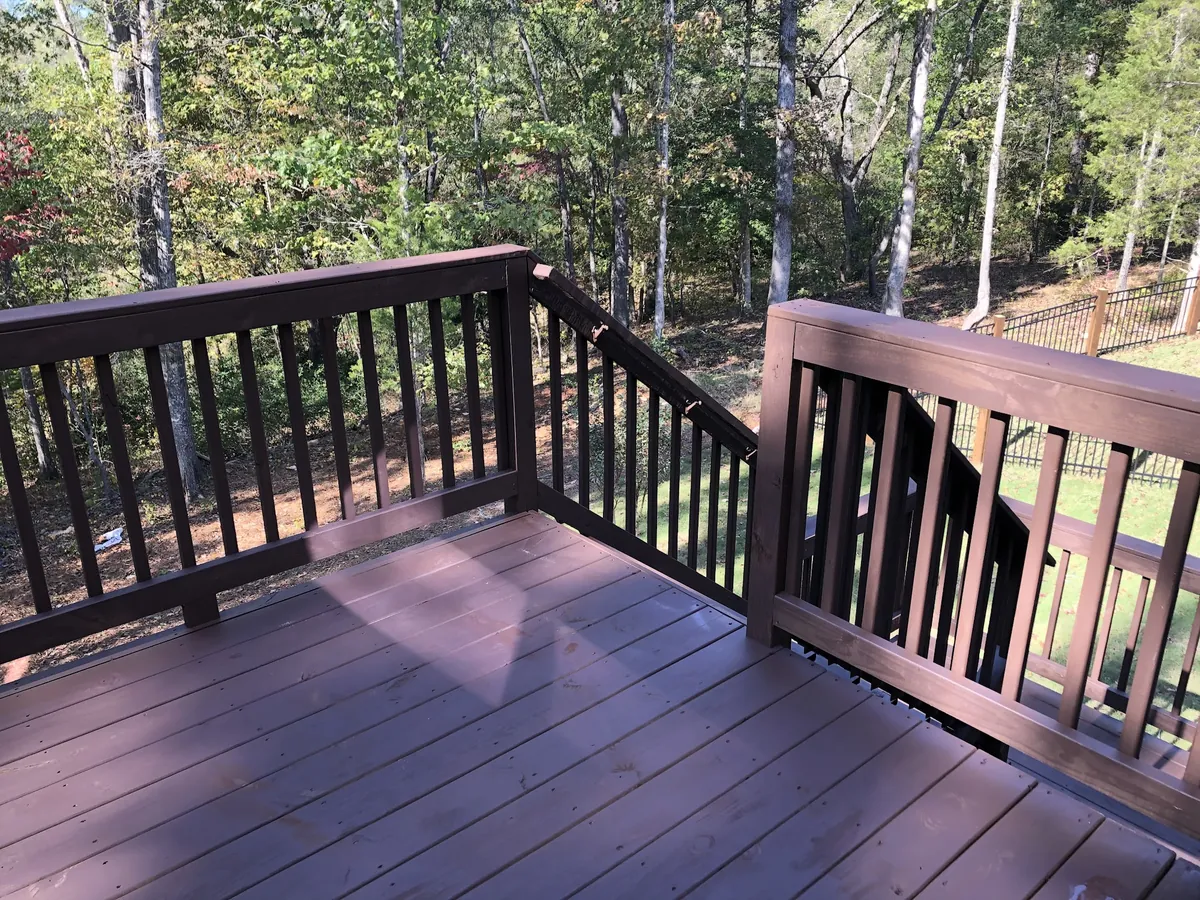 Deck and railings stained a deep brown in a wooded yard