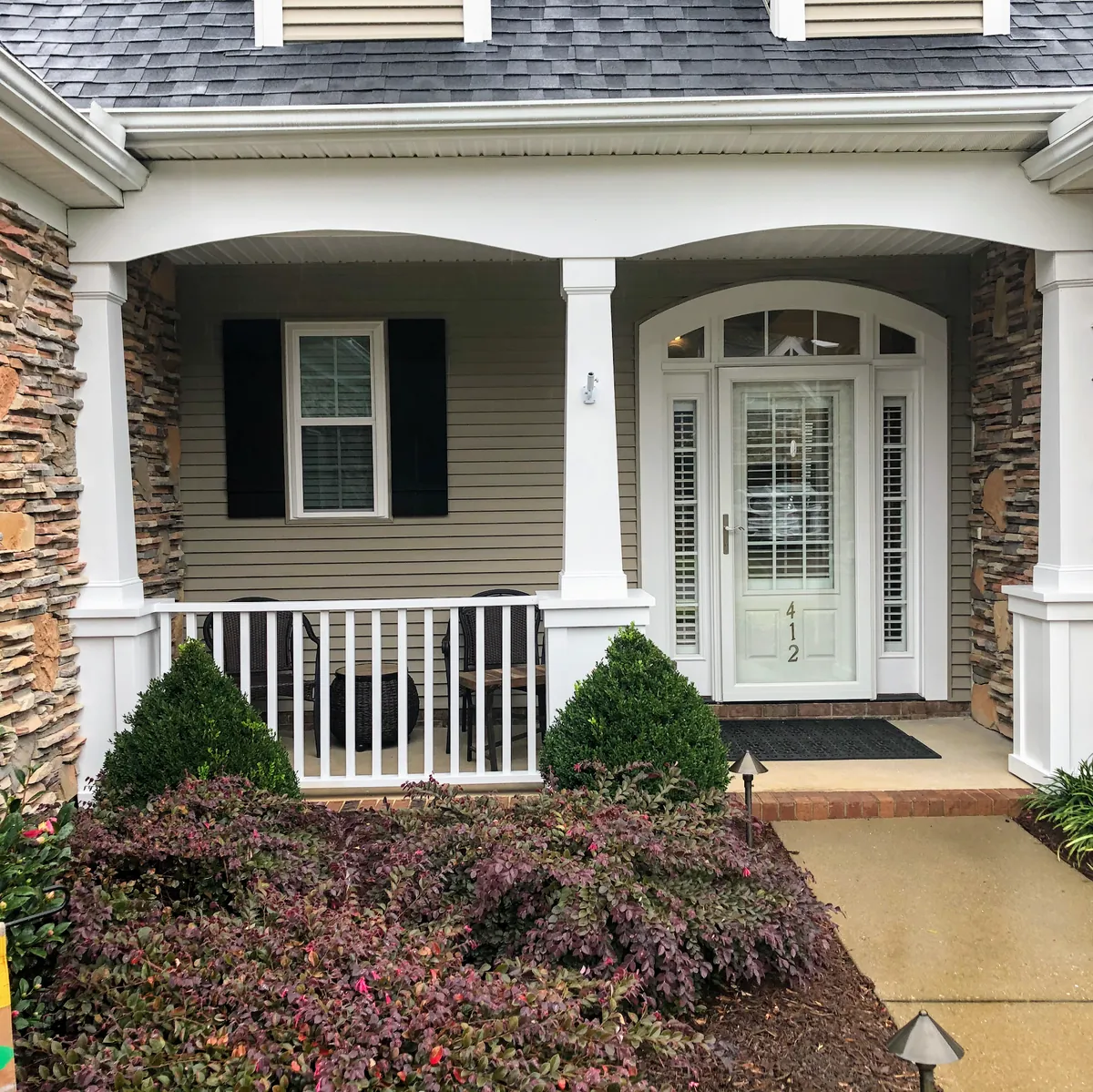 Front porch with white columns, railings and a freshly painted entry door