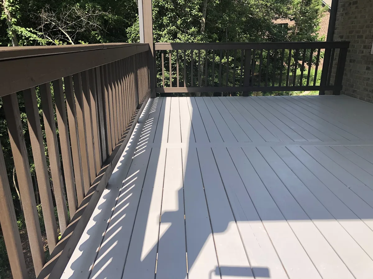 Porch floor painted gray with dark stained railings
