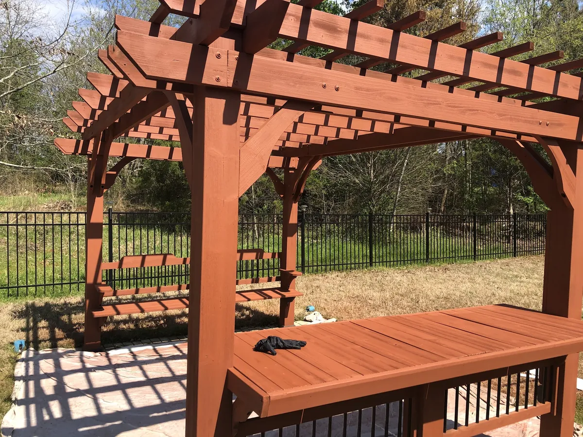 Wood pergola and bench stained a warm red-brown