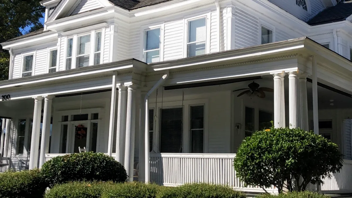 White two-story home with a wide wraparound porch